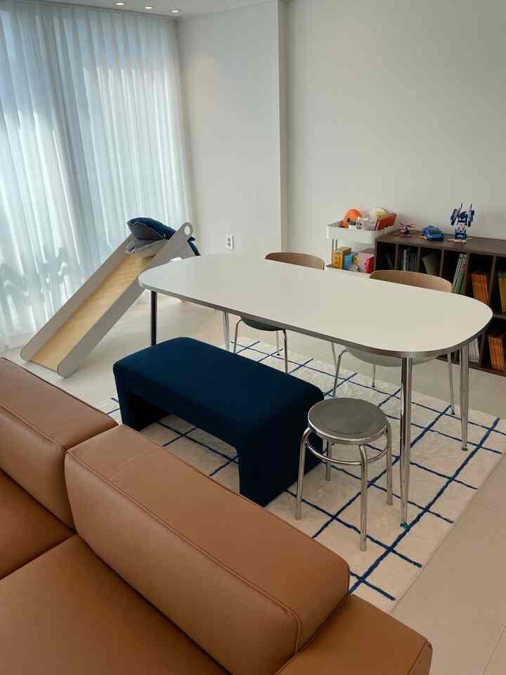 Bright white and brown toned dining room featuring children's slide, bookshelf, and cozy family seating area