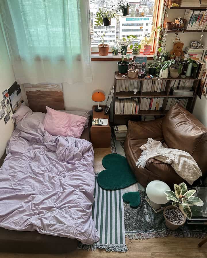 Natural tone small bedroom featuring a large bed, brown armchair, and various plants creating a cozy atmosphere