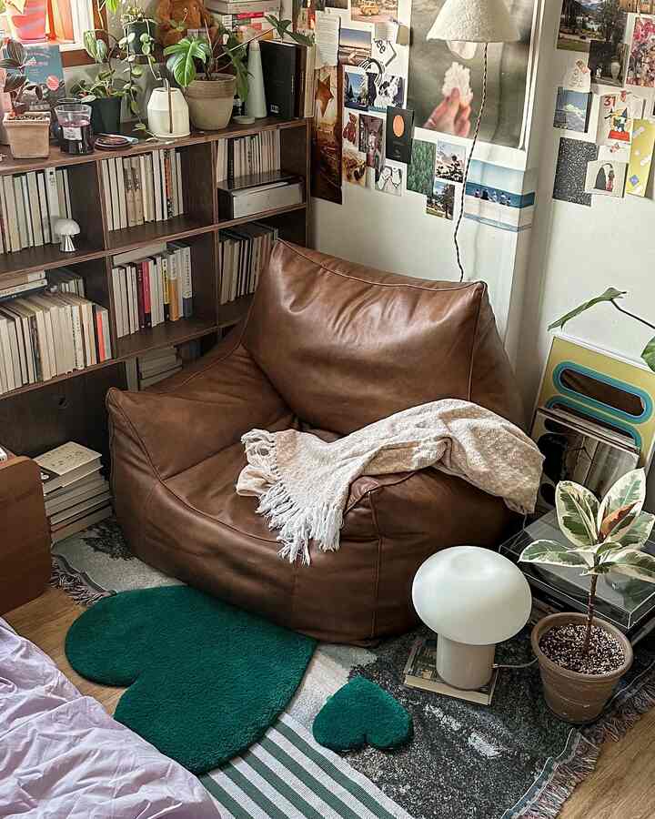 Cozy living room corner featuring a brown bean bag and green rugs, with a warm and natural atmosphere
