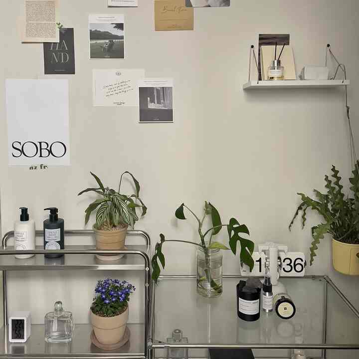 アイボリー色の壁とスチールモジュール家具が配置されたコンパクトな空間、植物と実用的な小物が自然な雰囲気のあるインテリア