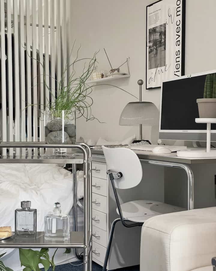 White and gray toned mid-century modern home office space featuring a tidy desk, plants, and a cozy atmosphere