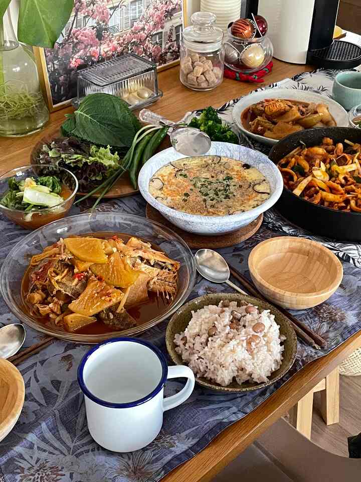 Natural brown-toned dining table set with various Korean homemade dishes and tableware in a cozy home party setting