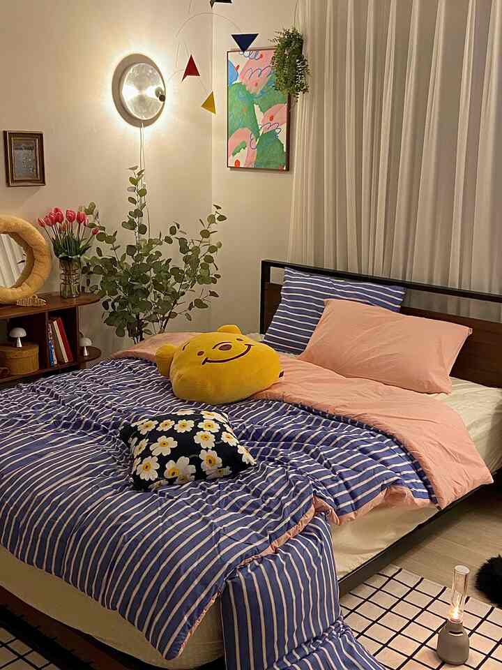 Navy and pink bedroom featuring striped bedding, wall art, and plants creating a cozy atmosphere