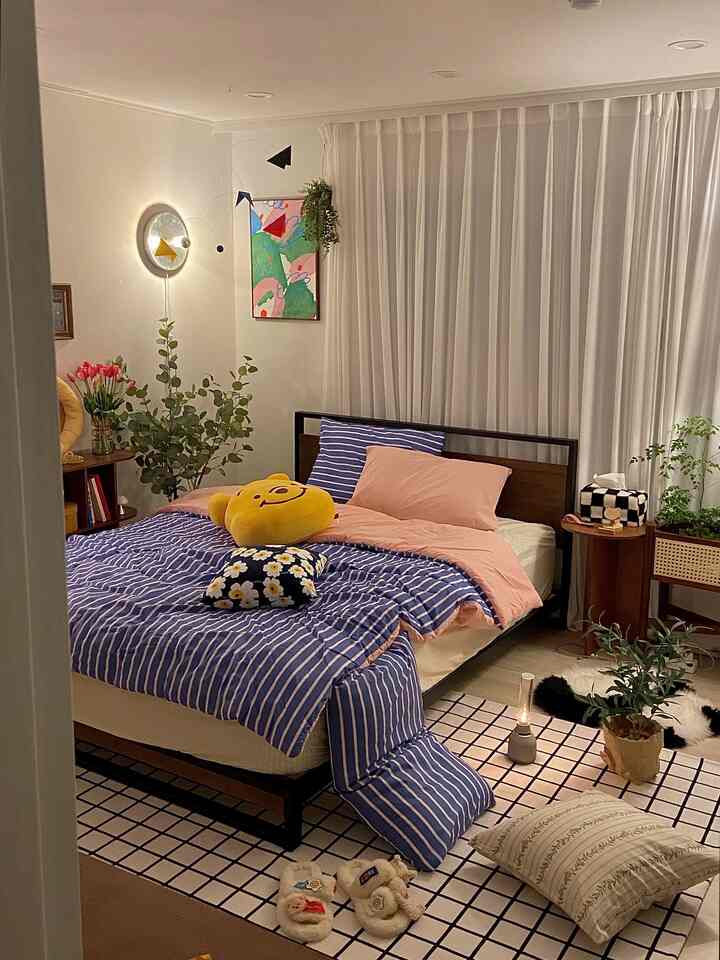 ナチュラルモダンの寝室、大きなベッド、白いカーテン、パターン付きラグ、植物が配置された雰囲気のある空間