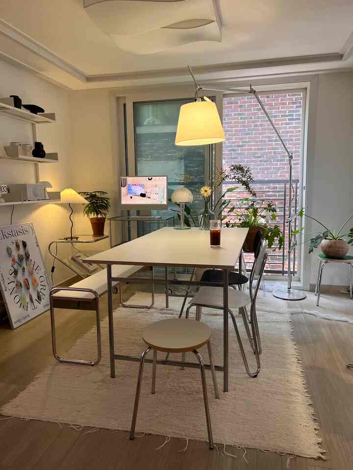 A modern living room with white and wood tones featuring a central long dining table and chairs in a cozy atmosphere