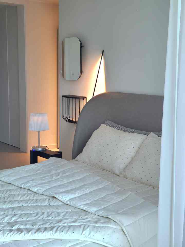 White-tone bedroom featuring a modern bed, nightstand, and floor lamp creating a cozy atmosphere