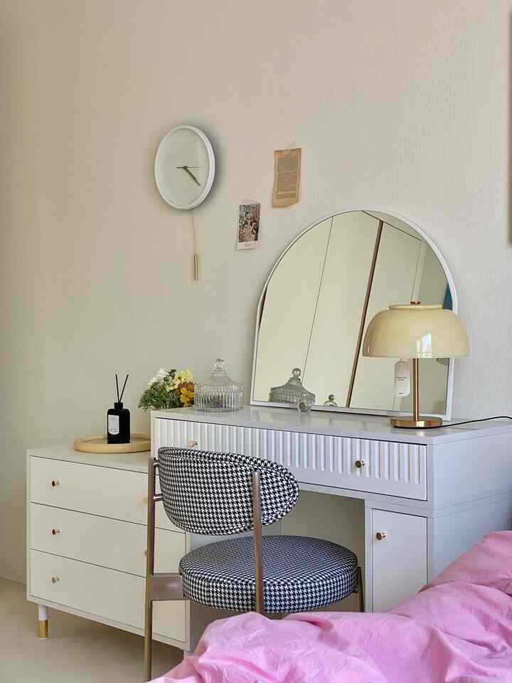 ホワイトとゴールドのアクセントがある寝室、化粧台と千鳥格子柄の椅子が配置された清潔感のある空間