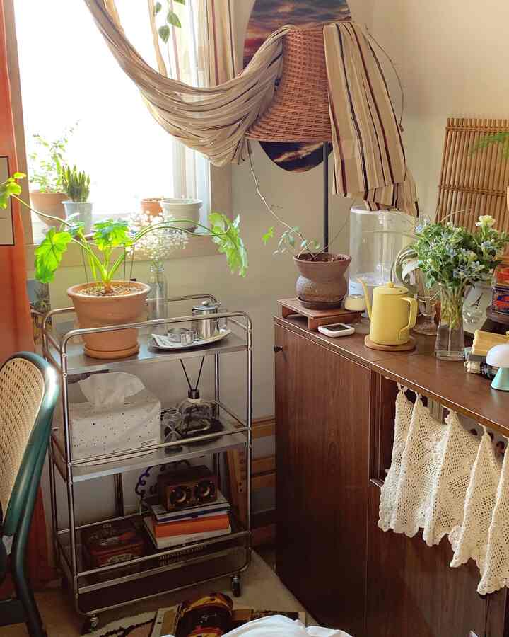 A cozy home cafe space in beige and brown tones featuring plants by the window and mid-century modern wooden storage cabinet
