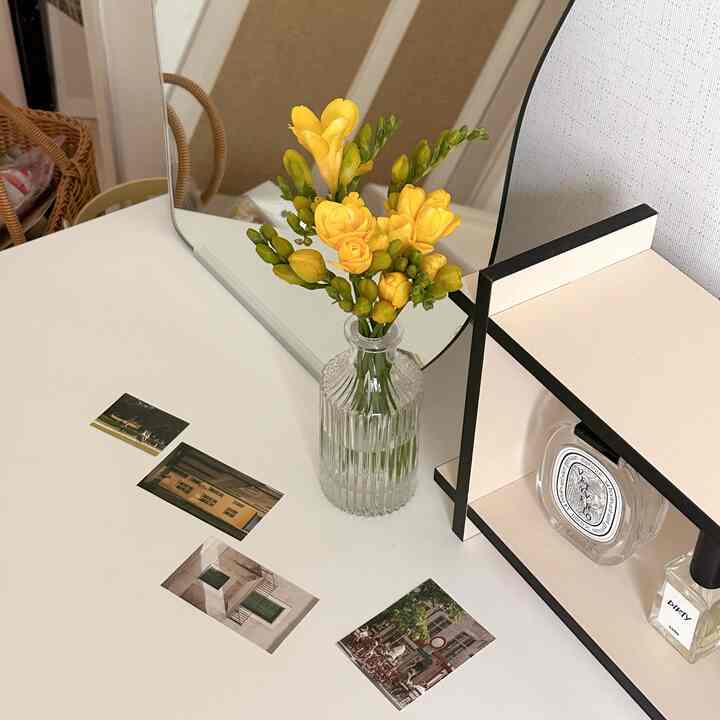 Bright, natural tone bedroom vanity featuring yellow flowers in a glass vase and a mirror, creating a cozy atmosphere