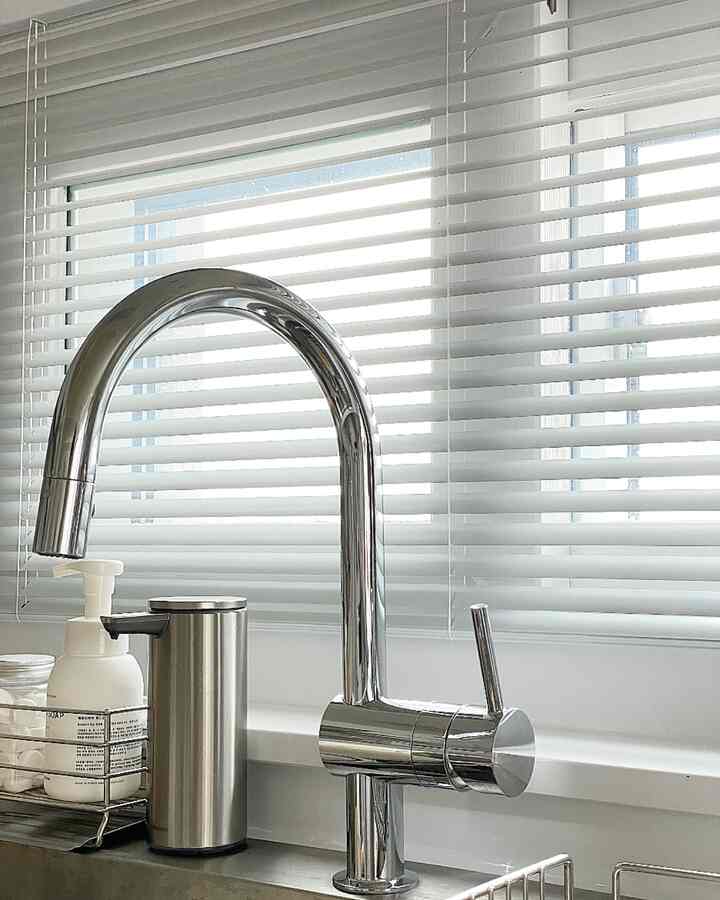 Bright-toned kitchen featuring a modern chrome kitchen faucet and stainless steel soap dispenser centrally placed, creating a clean aesthetic