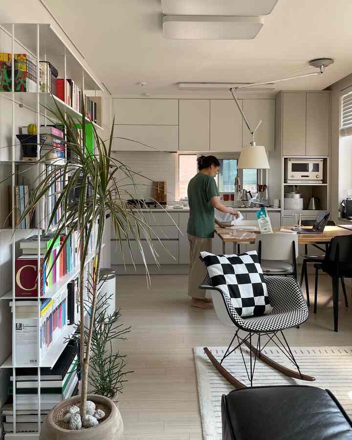ホワイトとウッドトーンが調和したキッチンとダイニングテーブルを備えた北欧スタイルのリビング、アームチェアと本棚が配置された印象的な空間