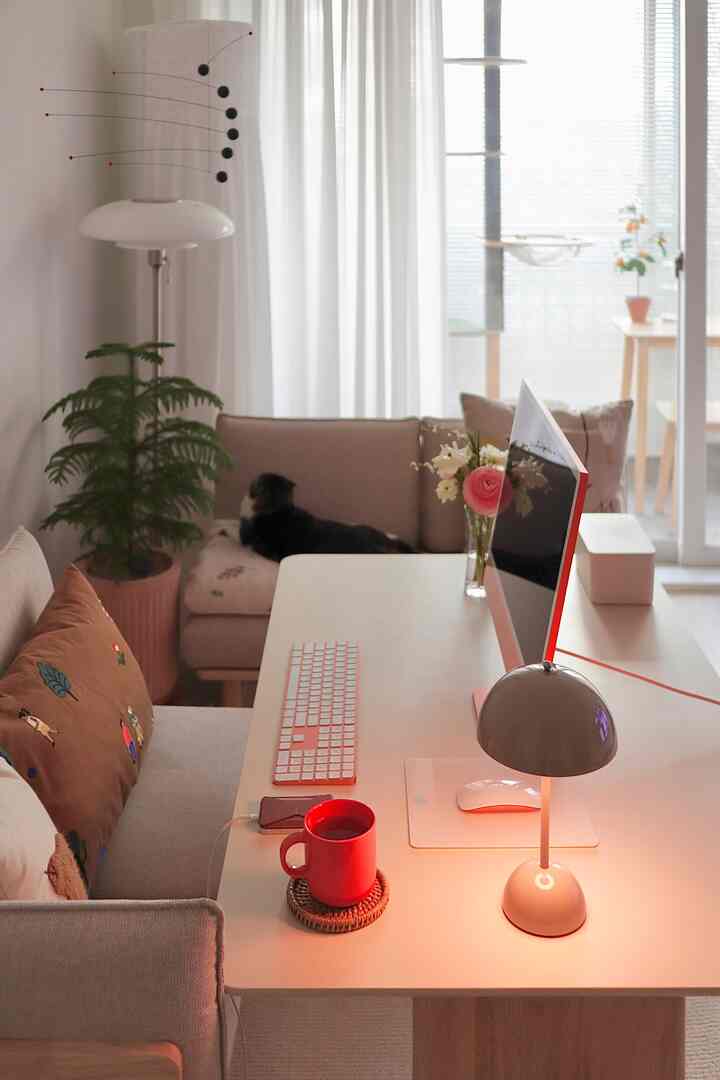 White and beige toned living room and home office with sofa and computer desk arranged in a cozy setting