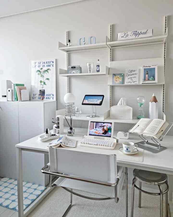 Modern study space dominated by white tones, featuring a white desk and chair with blue rug and decorative accents