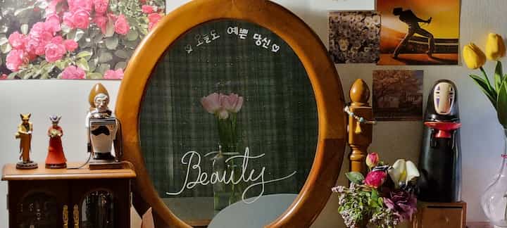 木目調と自然色が調和した小物とポスターが配置された雰囲気ある壁掛け鏡のインテリア空間