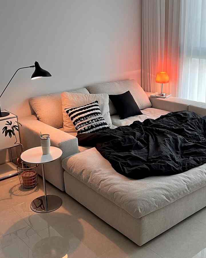 Bright beige modular sofa in white-toned living room, featuring black bedding and cushions creating a cozy atmosphere