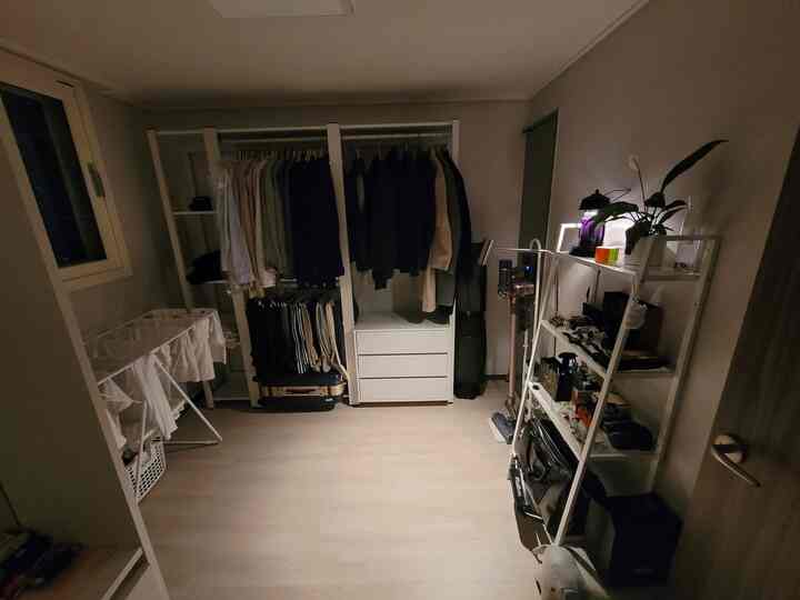 White and beige toned walk-in closet with storage furniture and clothing racks in a neat single household space