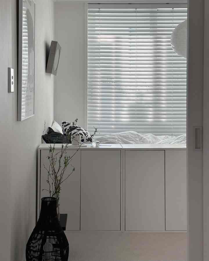 White-toned bedroom featuring a low cabinet used as room divider with a clean and minimalistic ambiance