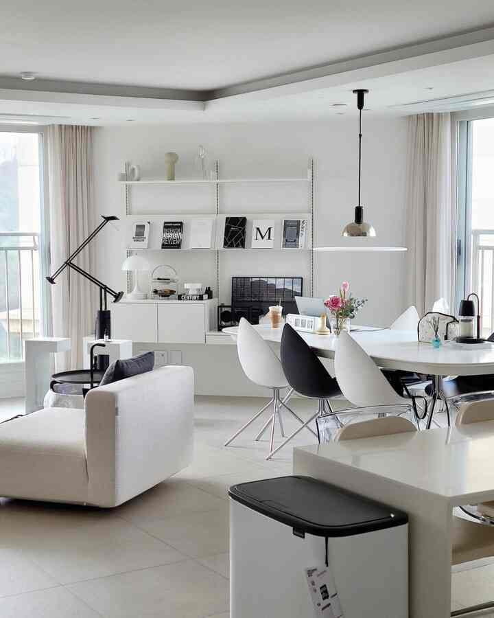 White and beige toned living and dining room featuring modern sofa, dining table, and tidy storage creating a cozy space
