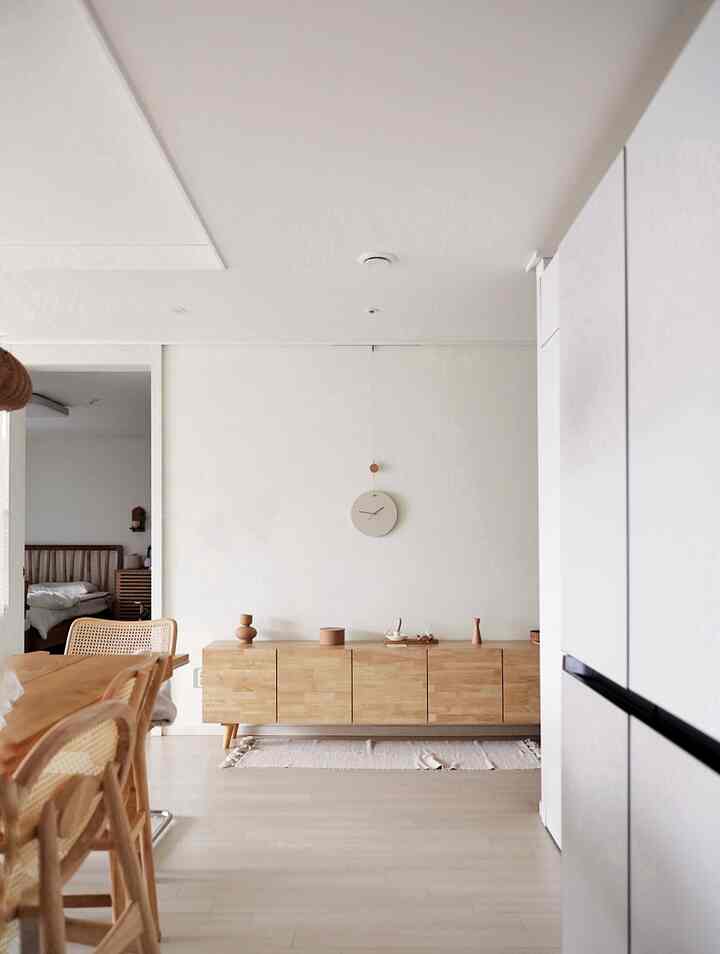 White-walled living and dining space for four-person household featuring wood tone furniture