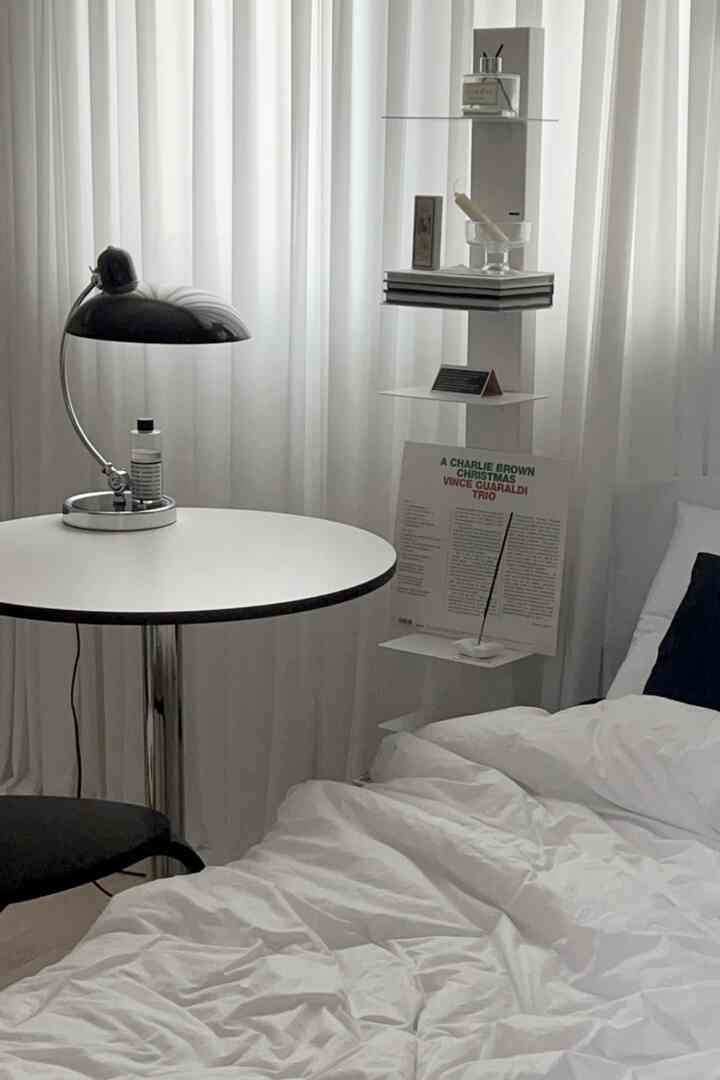 Monotone bedroom in white and black, featuring a round table, lighting, and tidy bedding with a calm atmosphere