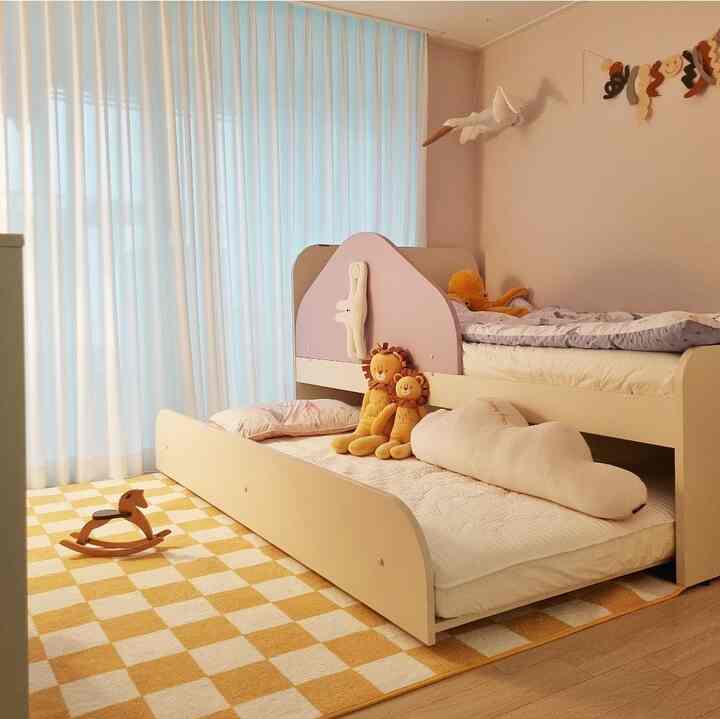 Yellow checkered rug and bunk bed in a kids' room decorated with charming toys and mobile