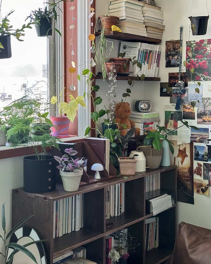 Natural-toned small study space featuring abundant plants, shelving, and vintage decor creating a cozy atmosphere