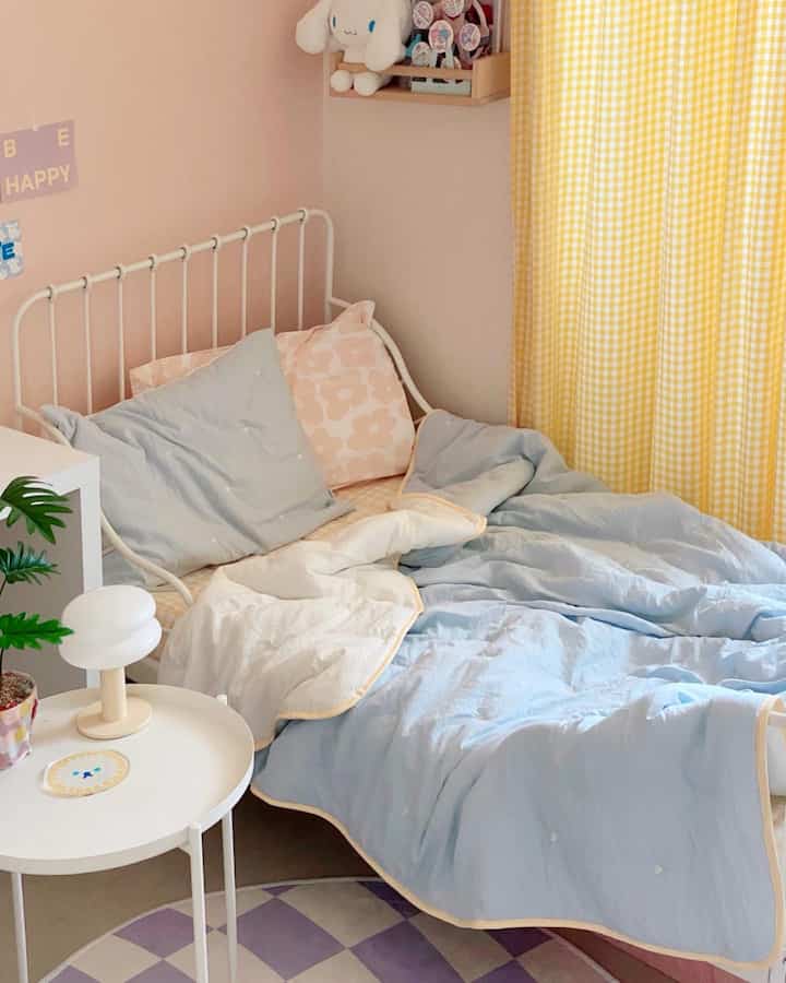 Soft pastel-toned kids' room featuring white bed and yellow gingham curtains in a cozy bedroom space