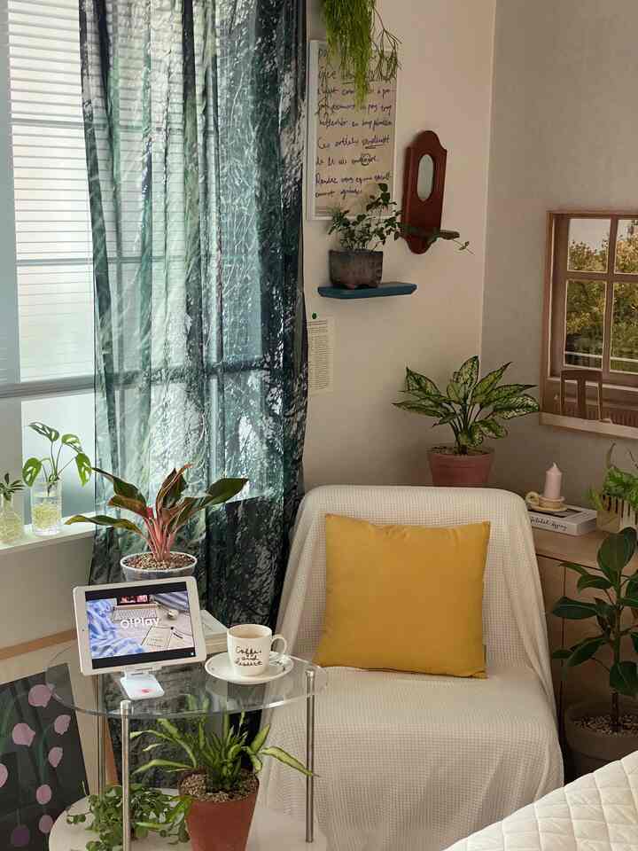 White and green toned bedroom featuring plants, posters, and a side table with a cozy natural atmosphere