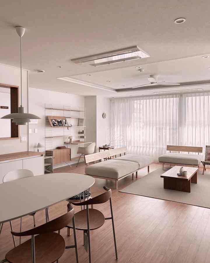 Bright and cozy living room in white and natural tones, featuring simple wooden furniture and large windows