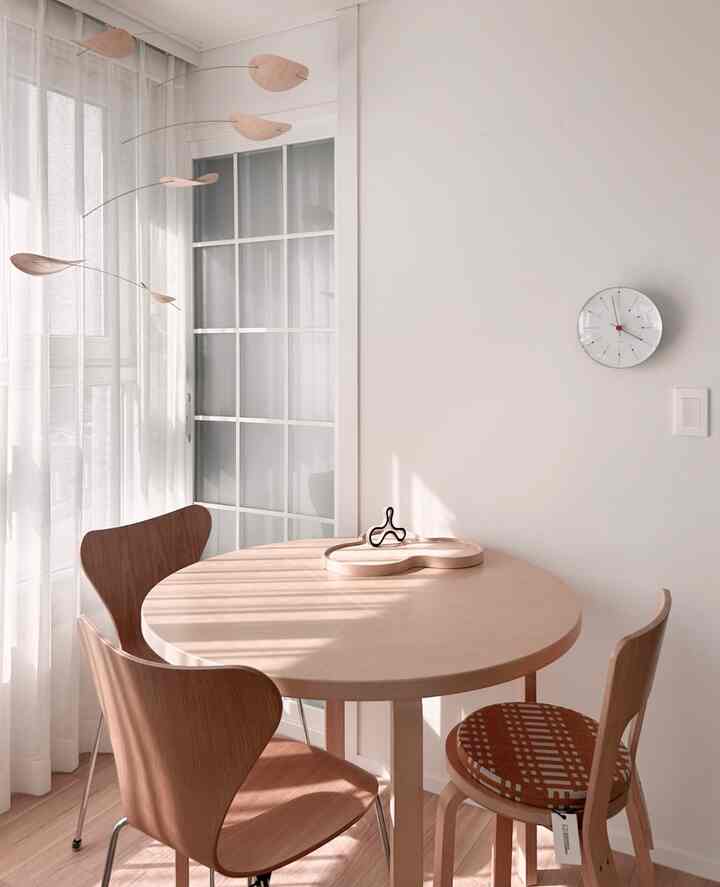 Bright white-tone dining area featuring a round wooden table and chairs bathed in natural light