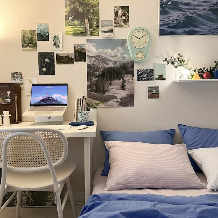 A small bedroom with white and blue tones featuring a desk and simple modern furniture
