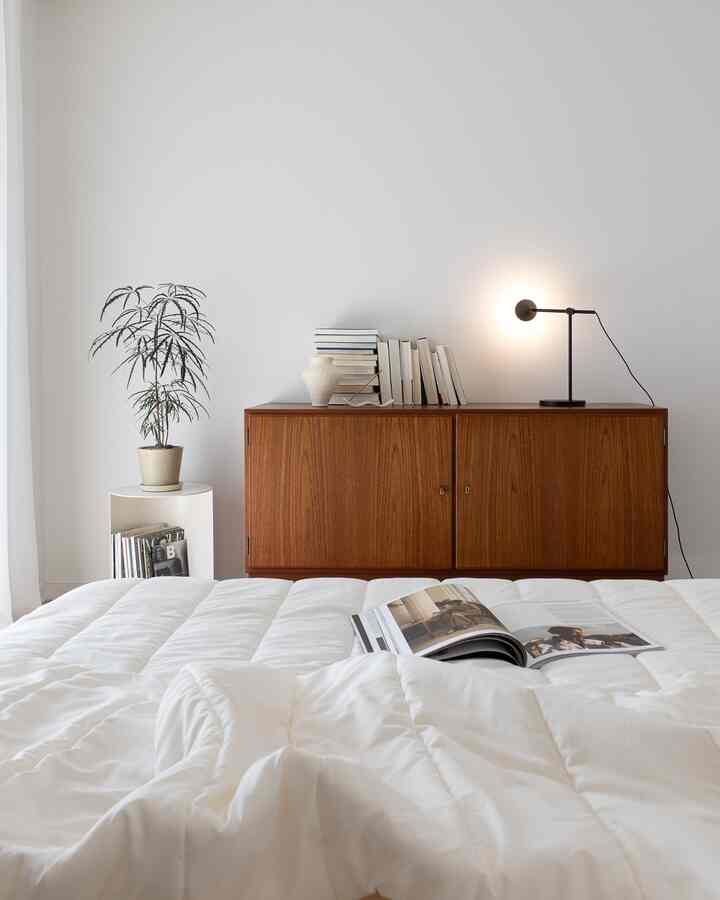 Bright white and brown toned bedroom featuring white bedding and wooden cabinet, creating a clean and natural atmosphere