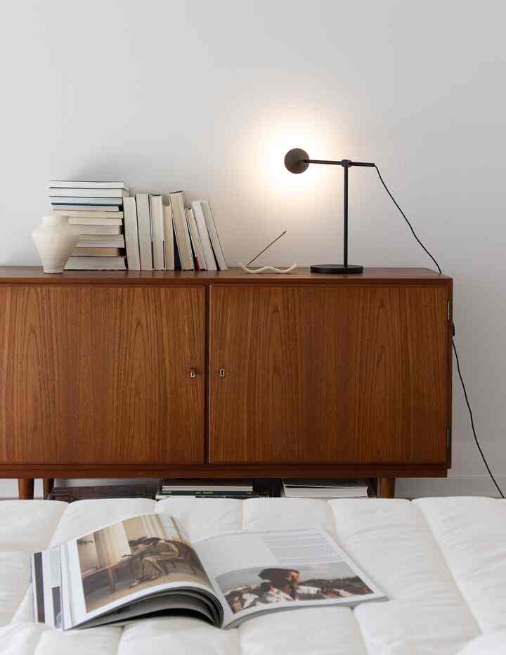 Natural toned bedroom featuring a wooden sideboard and a floor lamp, creating a simple and calm atmosphere