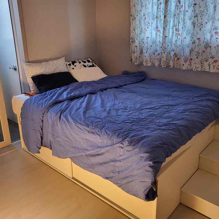 White and blue toned bedroom featuring a storage bed frame with a queen-size mattress in a compact space