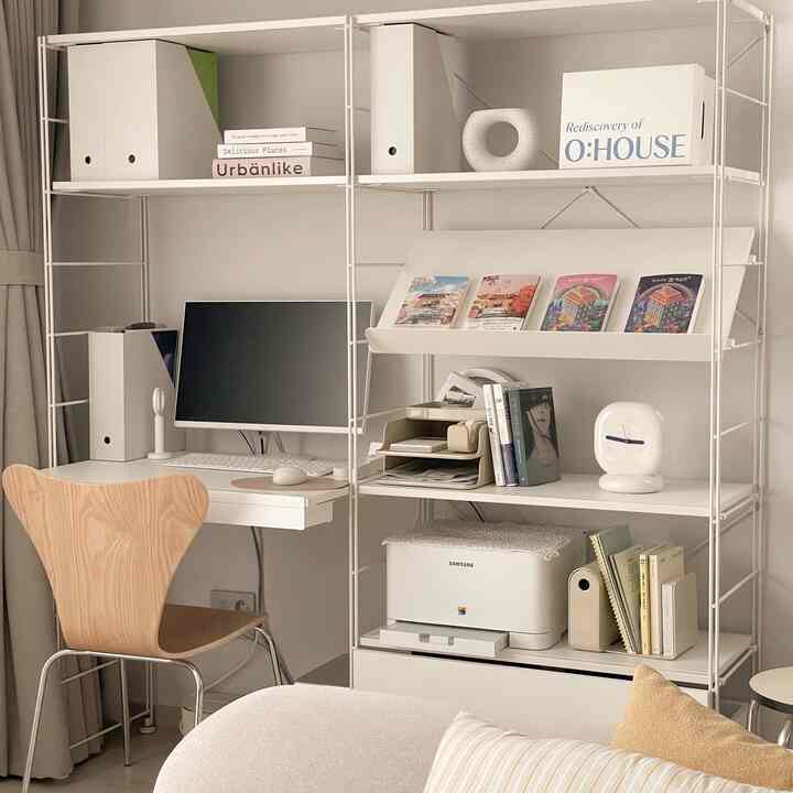 White and beige toned small home office featuring a desk, computer, and neatly organized shelving with modern decor