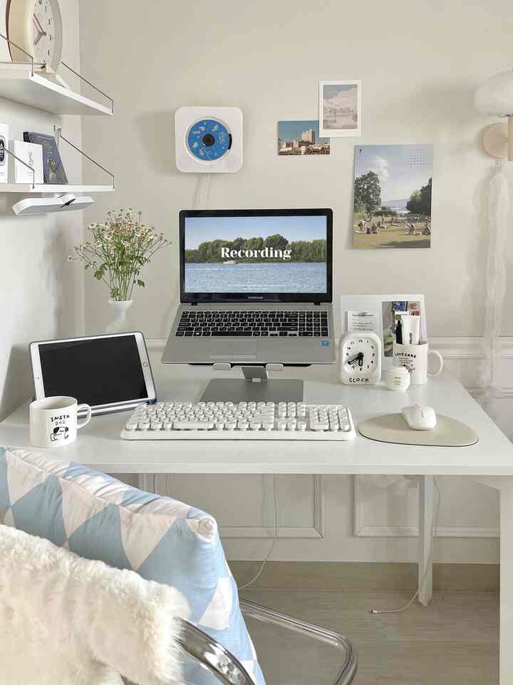 アイボリー色調のホームオフィス、中央にノートパソコンやキーボード、時計が整然と配置されたシンプルなデスクインテリア