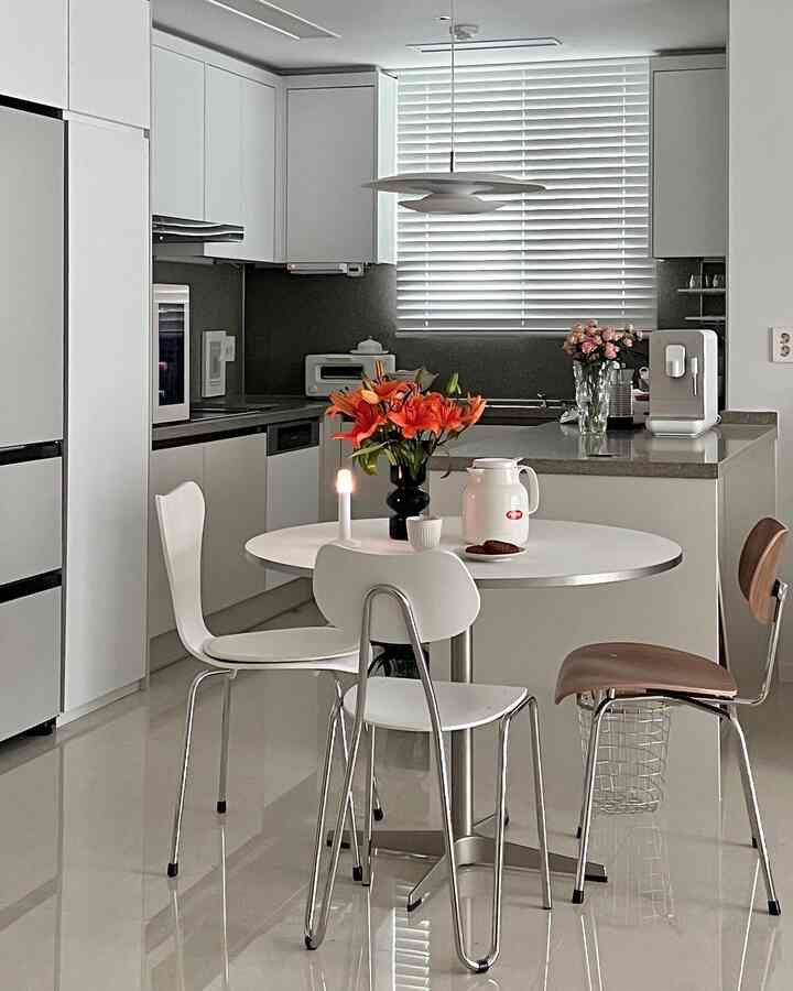 白とオレンジの調和が取れたキッチン、丸テーブルと椅子が配置された明るくモダンな空間