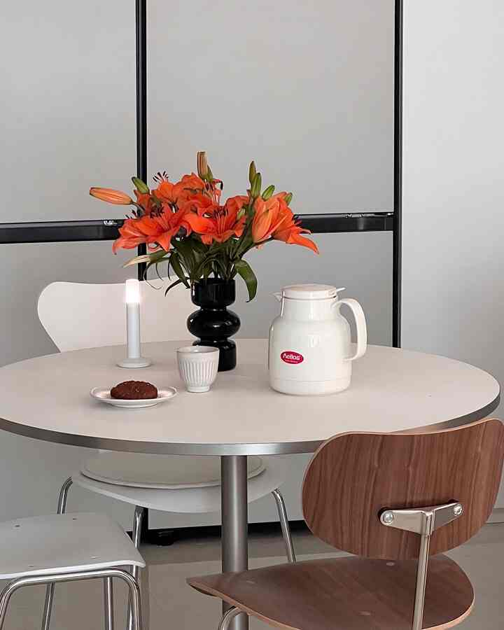 白と木目調のダイニングルーム、丸いテーブルに花瓶と保温ポットが置かれたシンプルなおうちカフェ空間