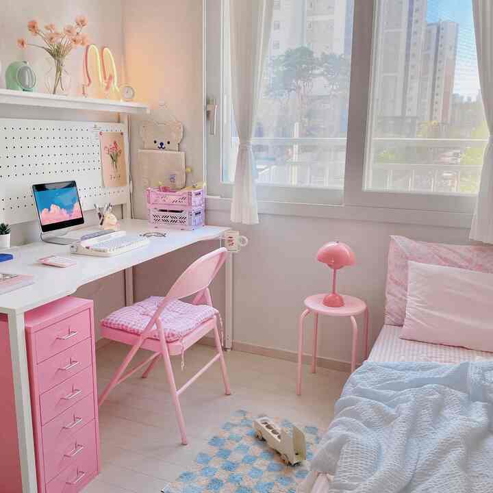 白とピンクの色調の小さな寝室、デスクとスツール、ベッドが配置された雰囲気のあるインテリア