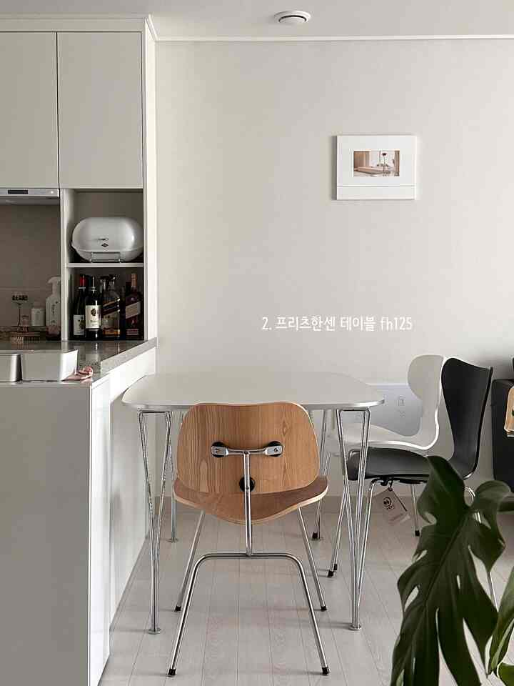 Modern minimal dining room with white tones and stainless steel legs, centered Fritz Hansen FH125 dining table