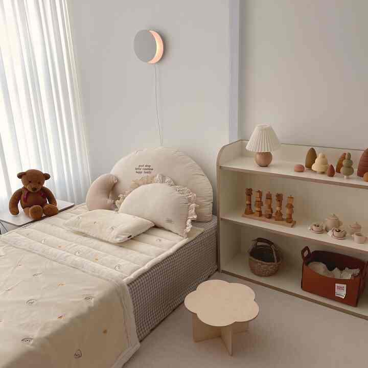 Beige and natural color-toned kids' room featuring a baby bed and wooden toy storage creating a cozy atmosphere