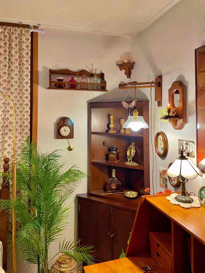 Cozy vintage-style corner space featuring wood tones, wall clock, wall shelves, and potted plant