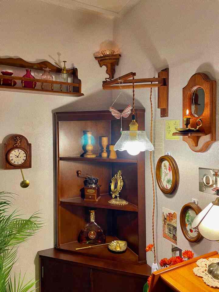 暖かいウッドトーンのヴィンテージコーナーストレージ、木製家具と壁時計・照明が配置された雰囲気のあるインテリア