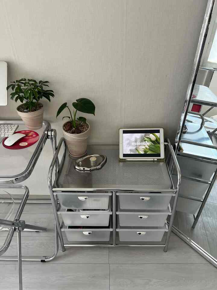 シルバーのクロム製引き出しと白い壁が特徴のホームオフィス空間、小さな植物とiPadが配置され、清潔で現代的な雰囲気のインテリア