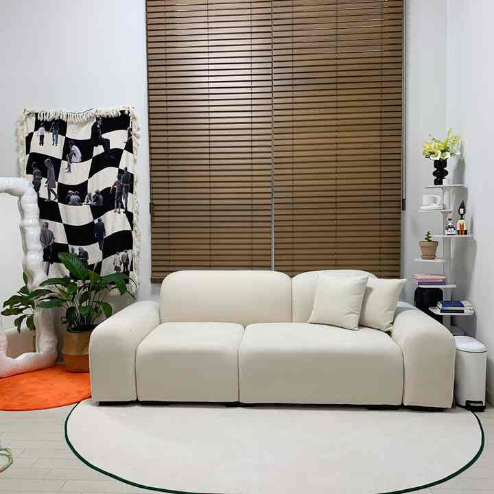 温かみのある木目調ブラインドと柔らかなアイボリーのソファが配置されたシンプルでミニマルなリビング