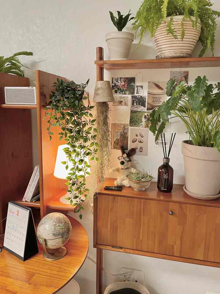 ナチュラルな色調のホームオフィス、木製家具と多くの植物が配置された雰囲気のあるインテリア