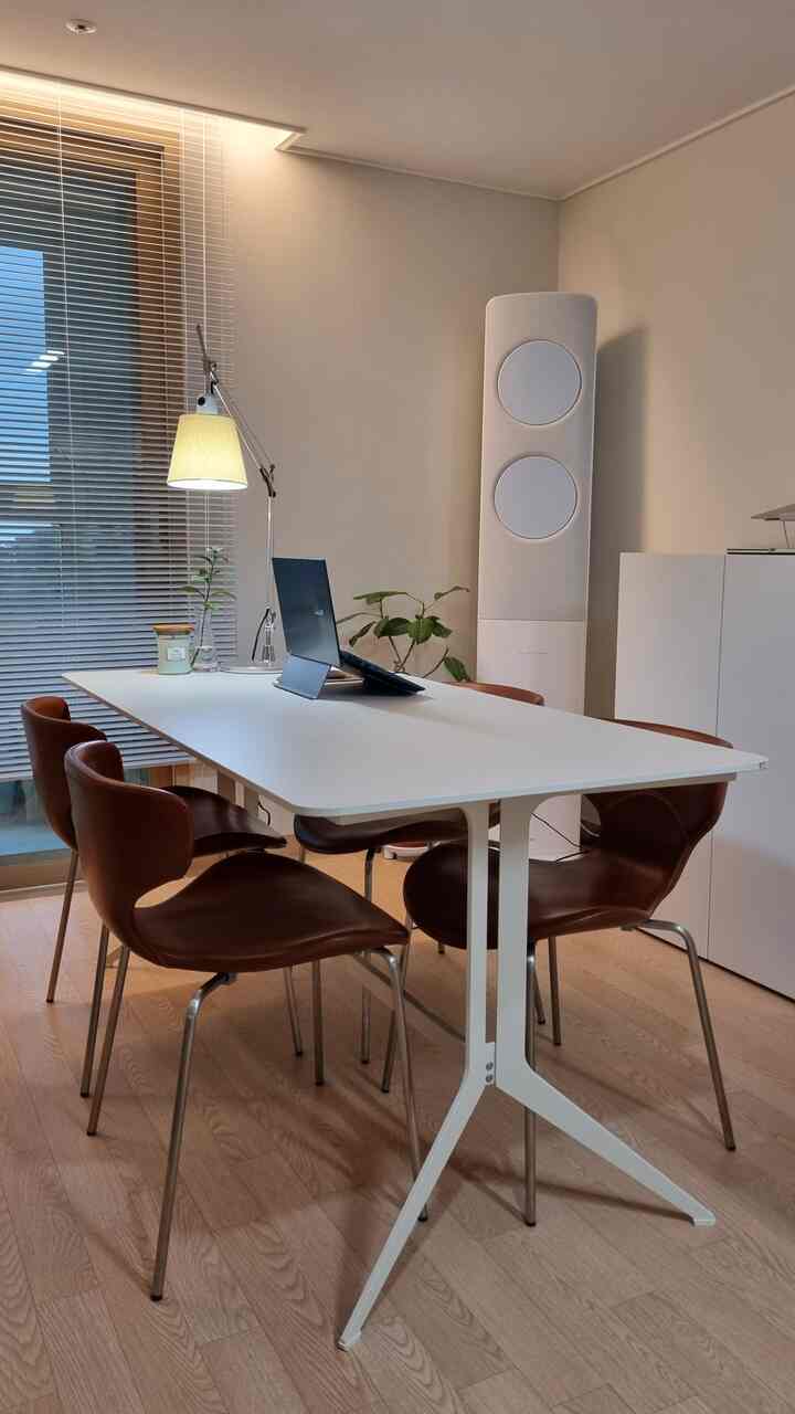 Modern and tidy home office space with white and brown tones, featuring a large table and leather chairs
