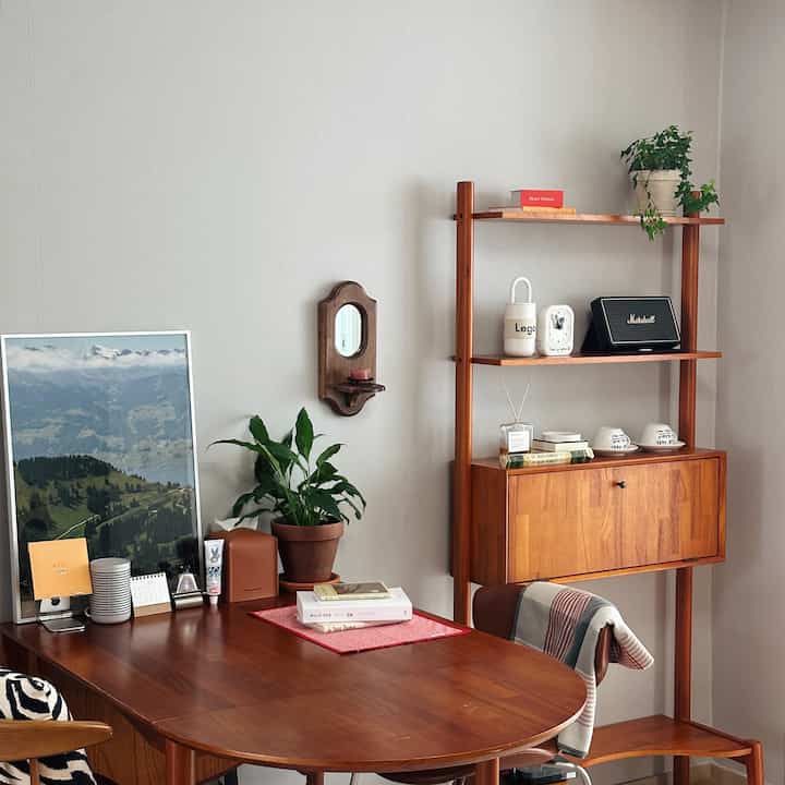 Natural wood tone dining room featuring a wooden dining table and chairs, wall-mounted shelf, and green plants in a cozy atmosphere
