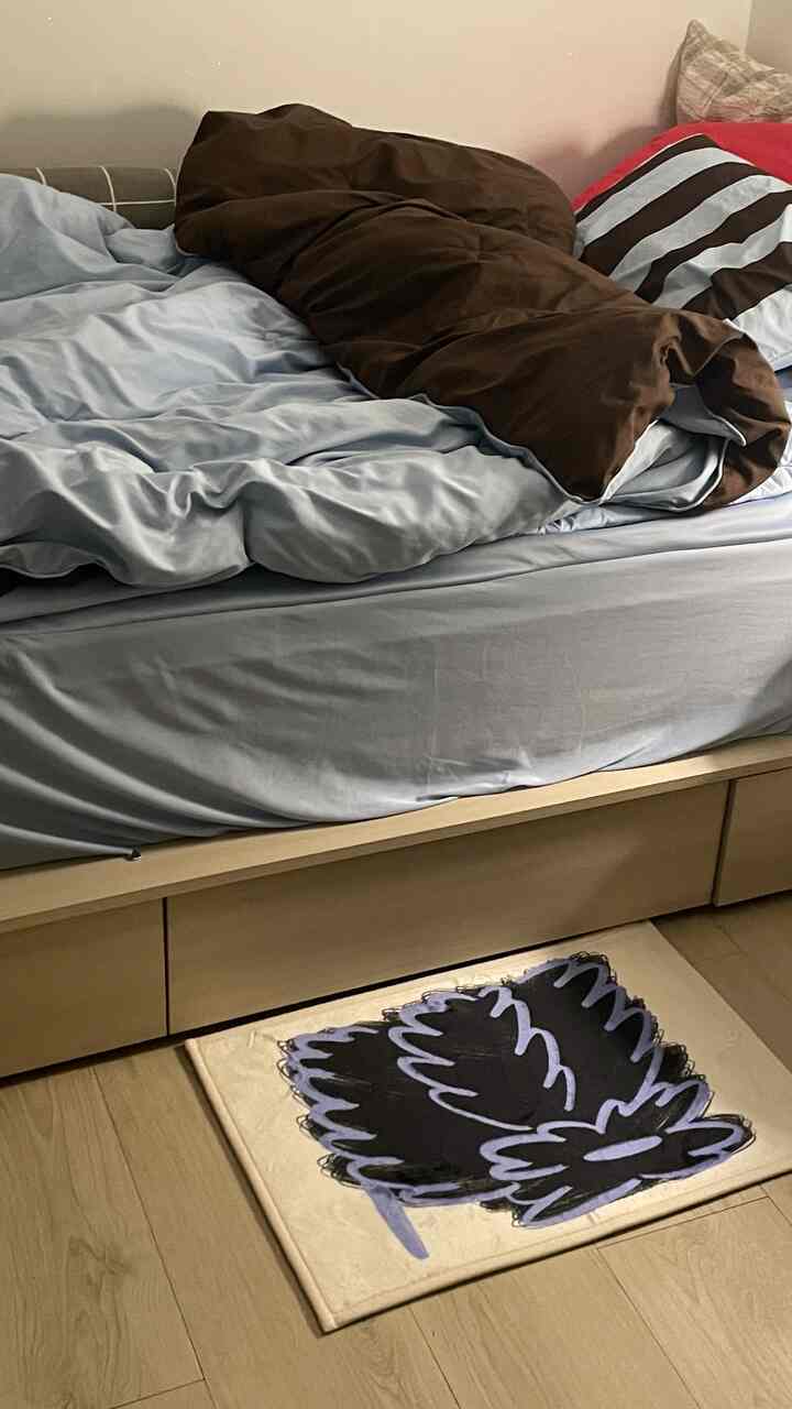Simple bedroom with wood tone floor and bed featuring pastel bedding and brown comforter