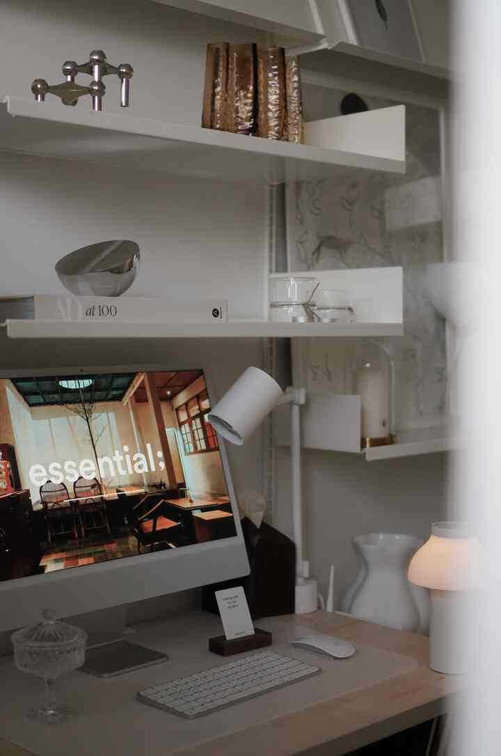 White and silver toned home office space featuring a computer and ambient lighting with a clean, organized work area